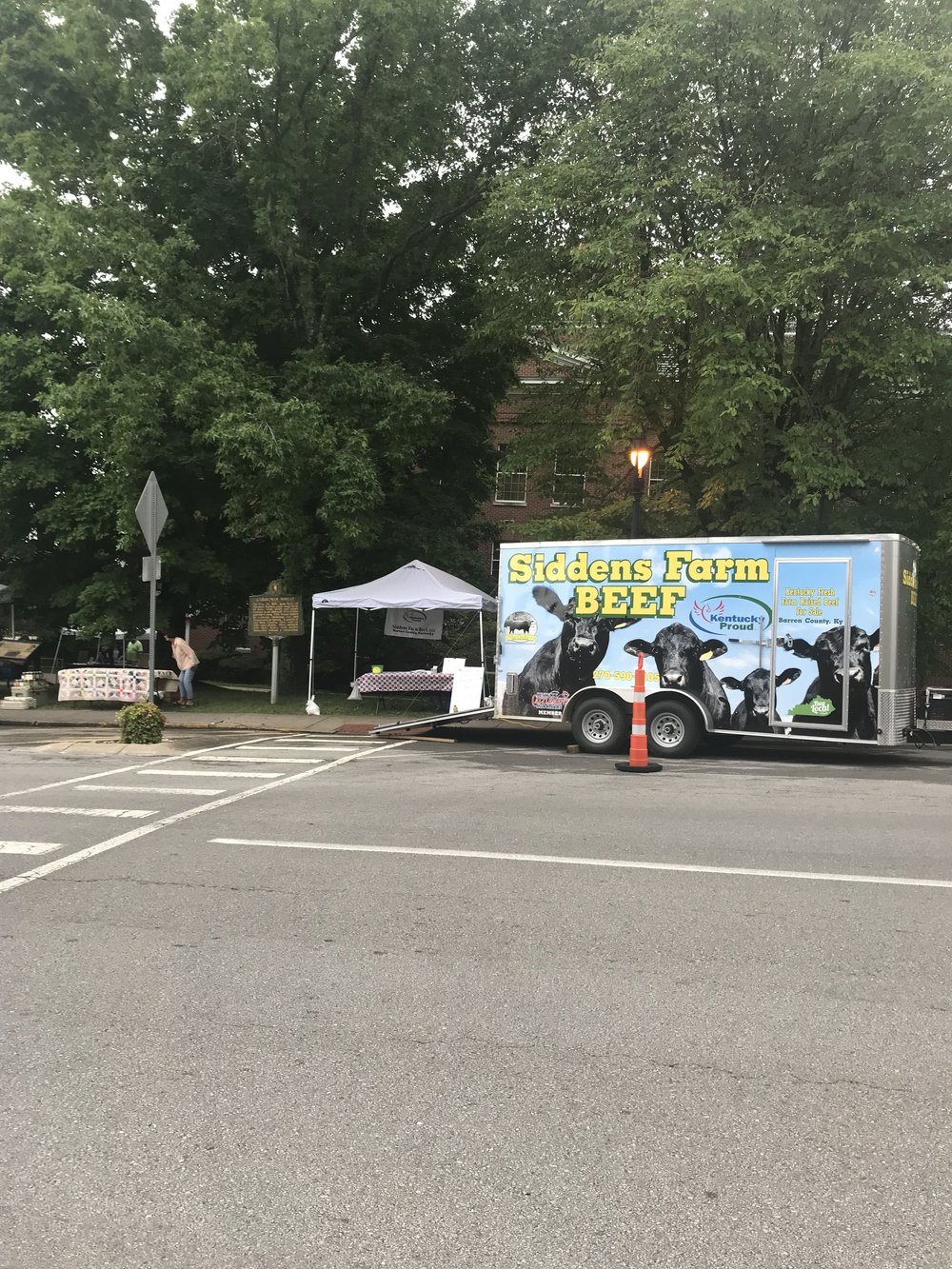 Robert+Siddens+-+IMG_1864 Siddens Farm Beef trailer at a local market, showcasing fresh beef products with a Kentucky Proud logo, surrounded by trees and vendor tents.